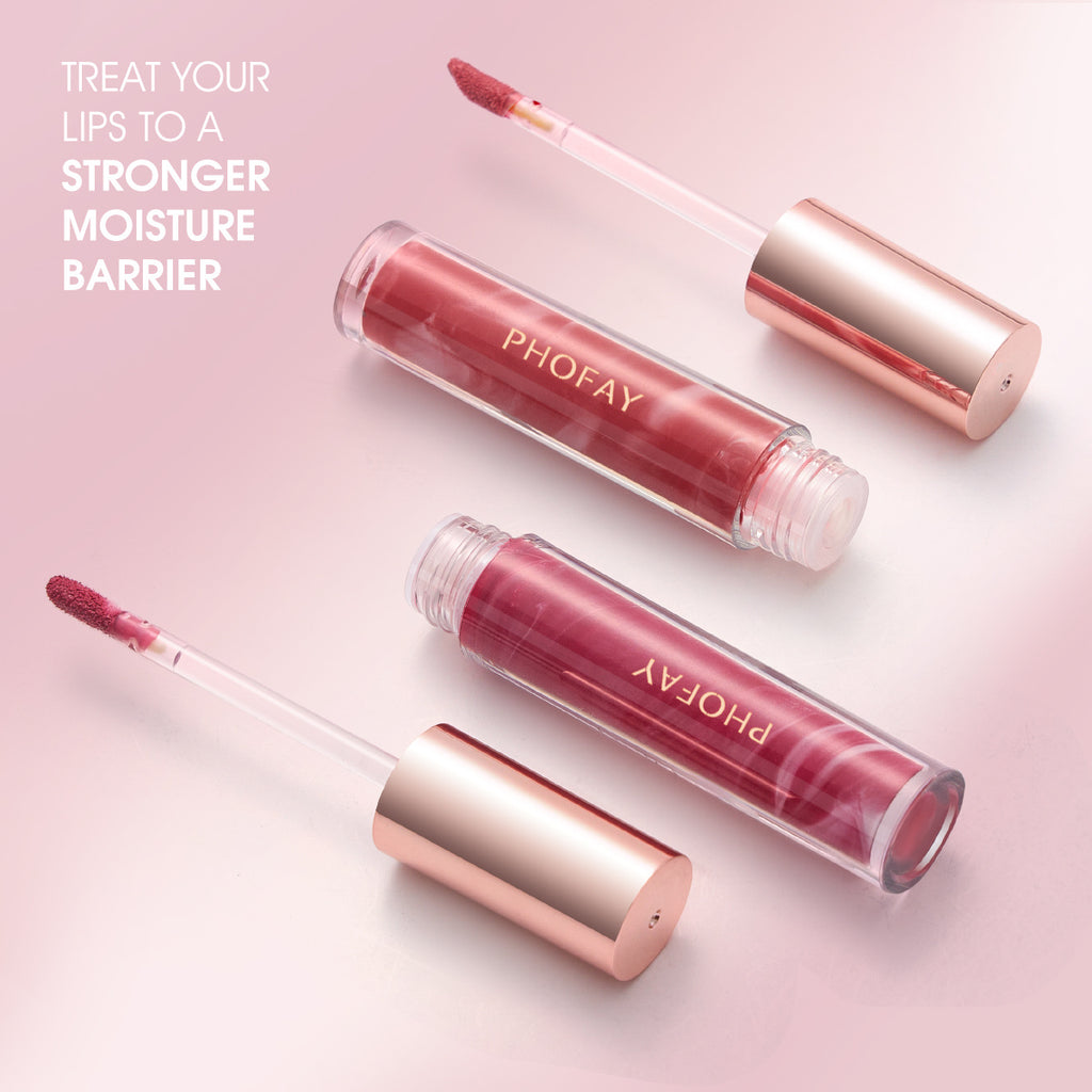 Three PHOFAY Rose Blooming Hydrating Lip Gloss tubes by PHOFAY Luxe Cosmetics with rose gold caps rest on a pink background. Two wands are open, showing applicators. Text: Treat your lips to a stronger moisture barrier with our hydrating formula.